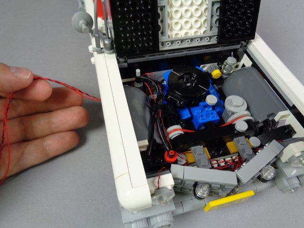 As shown in the second photo for this step, you should now have all wires under the hood pulled tight, and three wires should be coming out behind the front left wheel well: the two strobe light wires and the one red control wire.
