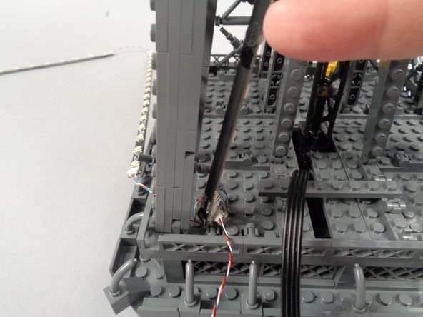 Remove the backs of the sticky dots on the second light strip (connected to plug #2 of the adapter board), and attach the strip to the tower frame as shown in the photos for this step.