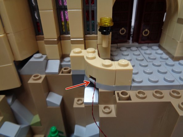 As shown by the red arrows in each photo, make sure the torch wire extends to the right as you re-attach pieces.