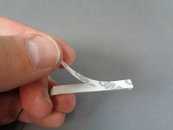 As shown in the first two photos, remove the self-adhesive backing from the light strip and mount the strip on top of the two black slopes so the light strip faces forward to the area behind the white panel as shown.