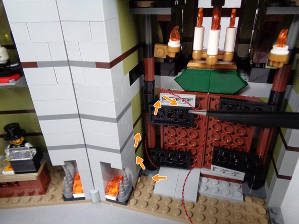 As shown in the second photo for this step, pull the wire back into the mansion, so it loops once around the hinge.