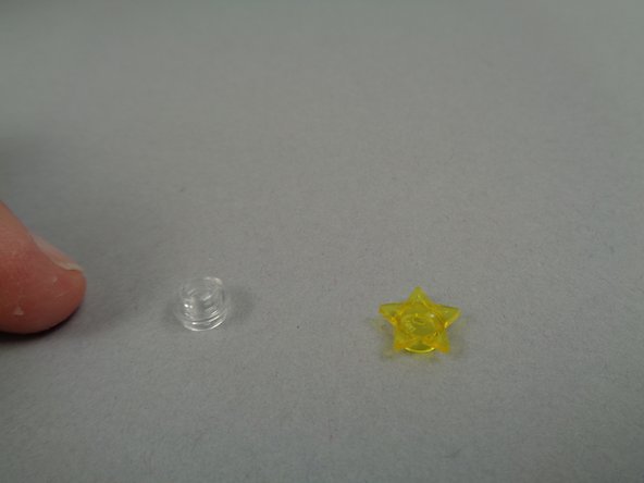 For this step, you will use the two remaining parts you took out of the &quot;Brick Parts&quot; bag earlier: the round 1x1 transparent plate with hole and a transparent yellow star.