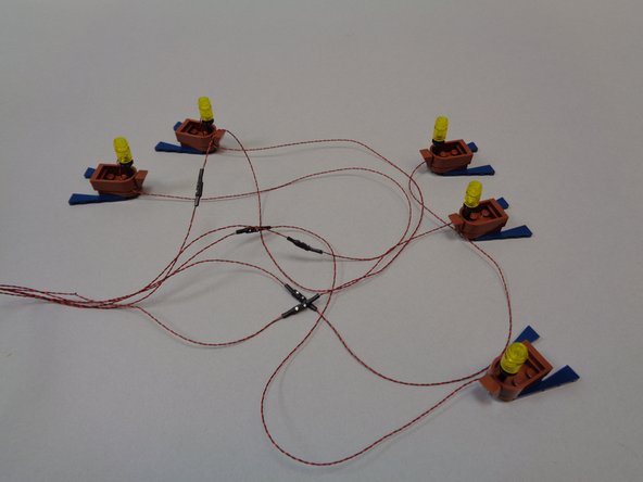 As shown in the second photo, each plug has a white dot on one side of its connector.  Match this white dot to the white dot on the wire from the boat lantern, and connect all five boats as shown in the third photo.