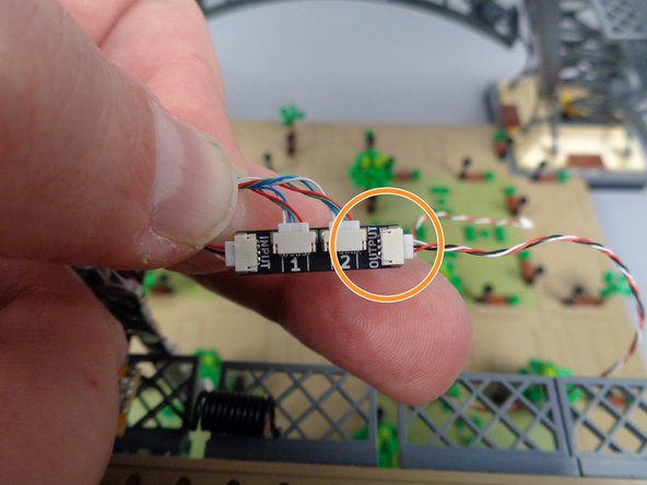 As shown by the orange circle in the second photo, take a second control cable and connect it to the OUTPUT plug on the adapter board.