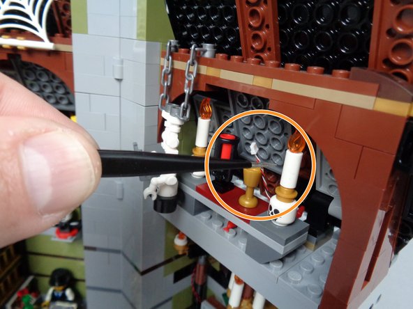As shown by the orange circle in the second photo for this step, you can use the tweezers included with your Brickstuff kit to help pull the control wire through from the inside of the mansion.