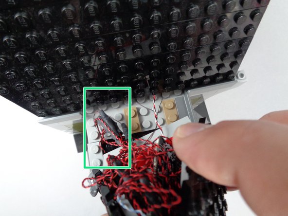 While continuing to hold the wires and adapter board in place beneath the roof, carefully re-attach it to the mansion.
