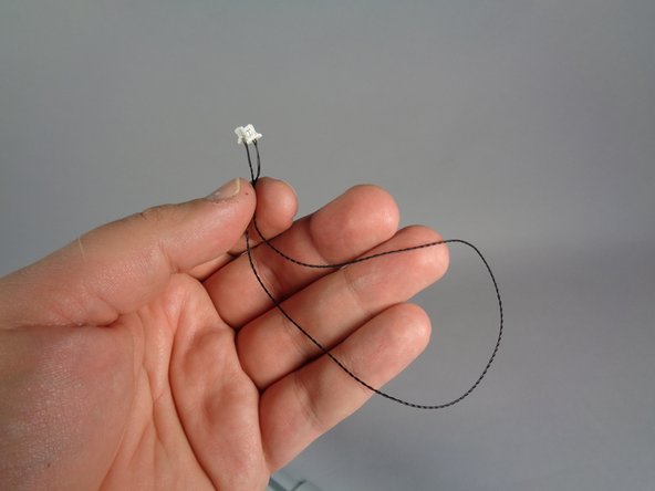 Next, take the black power wire from Bag 1 (shown in the first photo), and  pass it through the bottom of the head and up through the inside of the head as shown by the green arrows.