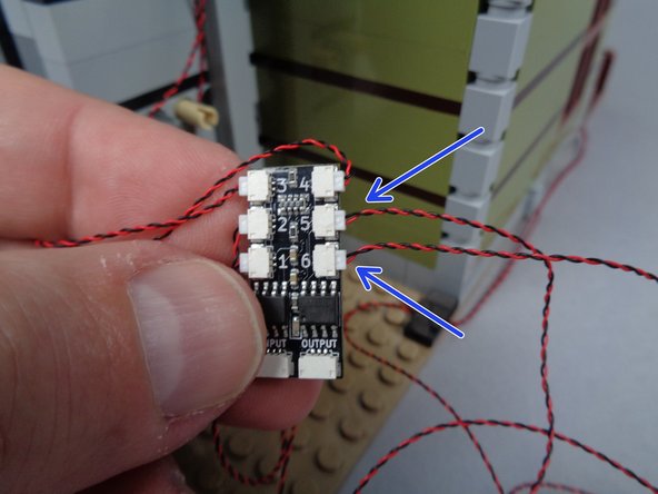 As shown by the blue arrows in the first photo for this step, connect the two LED light wires to plugs #5 and #6 on the BRANCH06X adapter board.