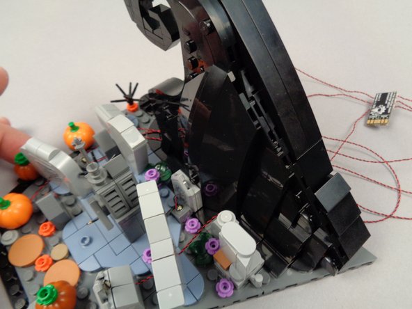 Aligning the wires with the gaps on either side of the 1x4 black tile will make it easier to re-attach the wave frame front.