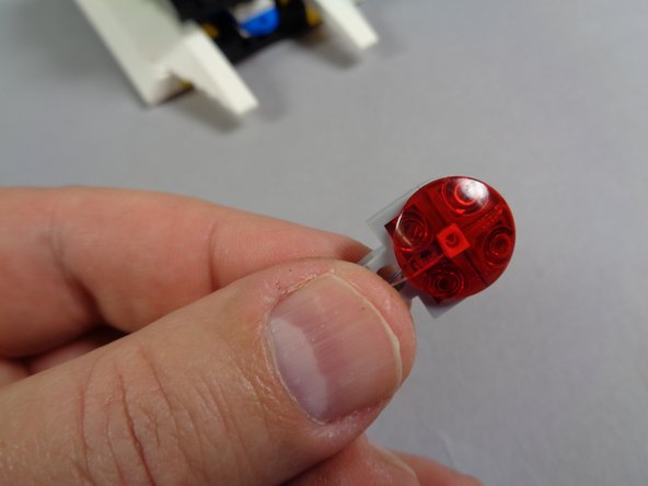 As shown in the third photo, carefully re-attach the transparent red round boat stud on top of the red LED light.