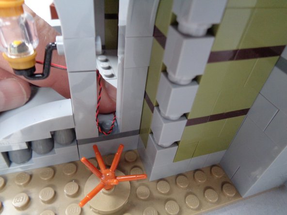 As shown in the photos for this step, run the light wire around the post under the railing and toward the front entryway.