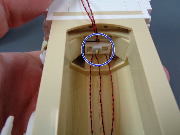 As shown by the blue circle in the first photo, take the warm white Pico LED light (with the white board) and use the last small sticky square from the &quot;Upper Level Interior Lights and Parts&quot; bag to attach it to the white 1x2 LEGO plate on the ceiling of the mirror room.