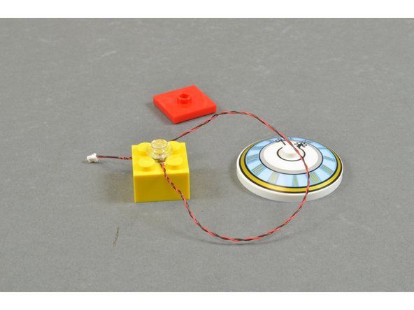 As shown in the second photo, separate the clock, 2x2 red LEGO jumper plate, and 2x2 yellow brick.