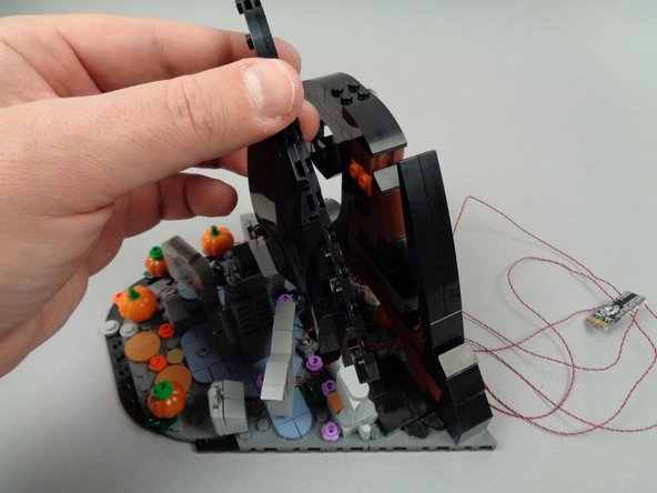 As shown by the orange circles in the first photo for this step, gather the LED light wires into two groups, and make sure each group is aligned with one of the two-stud gaps under the frame.