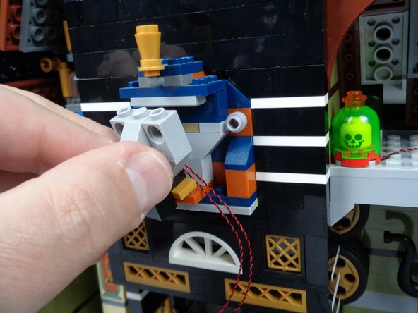 As shown in the second photo for this step, carefully re-attach the Pharaoh's face so that the two LED light wires pass to the RIGHT of of the face.