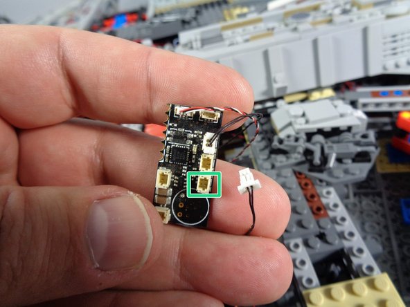 As shown by the green rectangle in the first photo for this step, carefully disconnect the black wire from the bottom side connector on the old TRUNK05 controller.