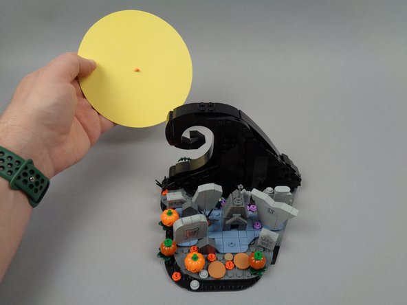 As shown in the photos for this step, remove the paper moon, then remove the front of the large black wave assembly.