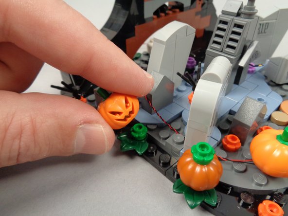 As shown in the first photo for this step, remove the back pumpkin from its green flower plate.