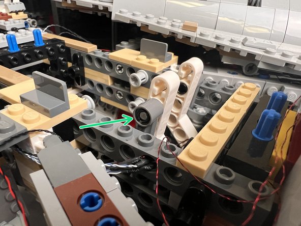 Re-attach the white Technic arm, and close the boarding ramp. Make sure the ramp closes with the magnet facing the outside of the frame as shown by the green arrow in the first photo.