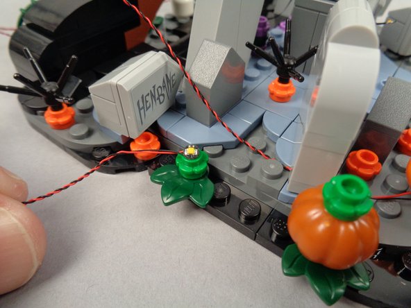 As shown in the second photo, place the remaining LED light from the orange dot bag on top of the green flower plate.