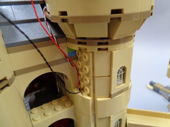 At the same time, take the wire and run it UP the channel.  See the green arrows in the photo.  Use one tan slope to hold the wires in place as shown in the second photo.