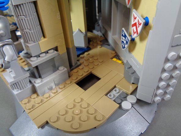 As shown by the blue rectangle in the third photo, re-attach the dark tan 2x4 plate you removed earlier on top of the two long tiles.