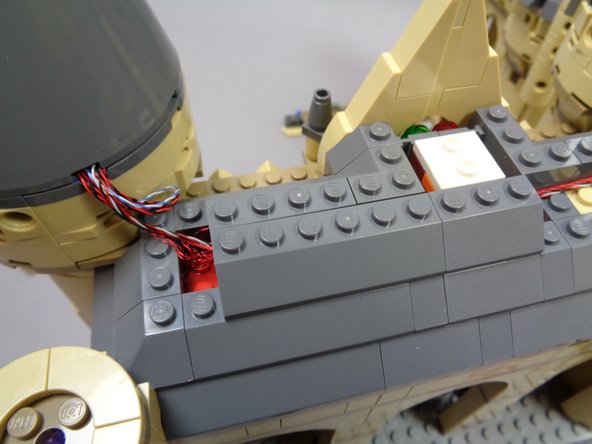 As shown in the second and third photos, carefully replace the roof pieces on the left side of the roof so the two control wires are covered.