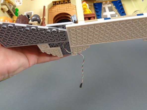 As shown in the first and second photos for this step, you should have two black connecting plugs, one coming out of the bottom of the middle section of the castle (second photo) and the other on the lower base of the castle (first photo).