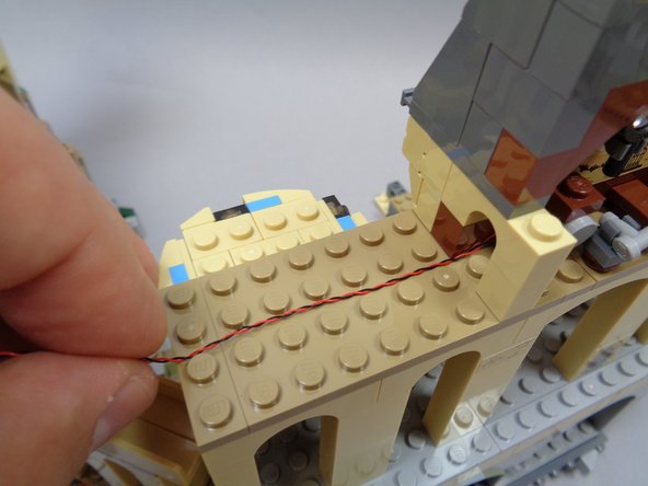 As shown in the third photo, make sure the wire from the light in the Defense Against the Dark Arts classroom is positioned flat along the dark tan plate, and that the wire runs between the studs.