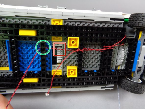 As shown by the blue circle in the first photo, loop the two strobe light wires several times through the black Technic frame, and place the red control wire under the wire loop.  Loop the strobe light wires several times through the Technic frame to hold the red control wire in place.