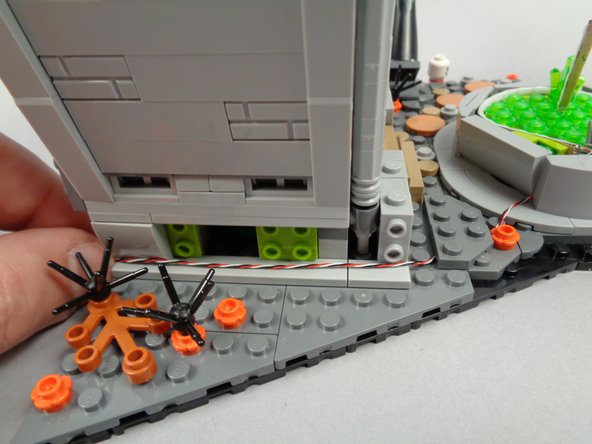 As shown in the third photo for this step, route the light strip wire along the bottom base of the town hall, making sure the wire passes beneath, not on top of, any studs.