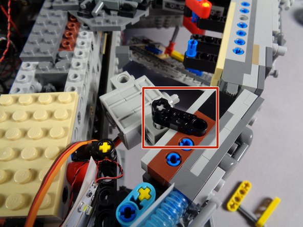 As shown in the photos for this step (and by the red rectangle in the first photo), attach the second black lever to the top of the axle and to the top of the Falcon frame.  This should hold the servo firmly in place, yet allow it to rotate slightly.