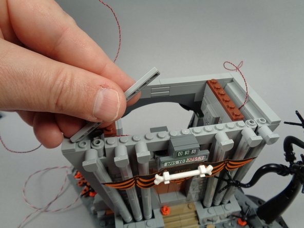 As shown in the photos for this step, re-attach the two long tiles to the top front of the town hall.