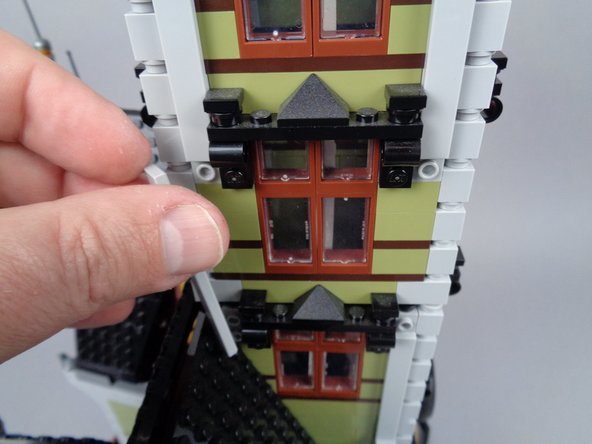 As shown in the photos for this step, re-attach the long LEGO tiles on three sides of the tower to secure it.