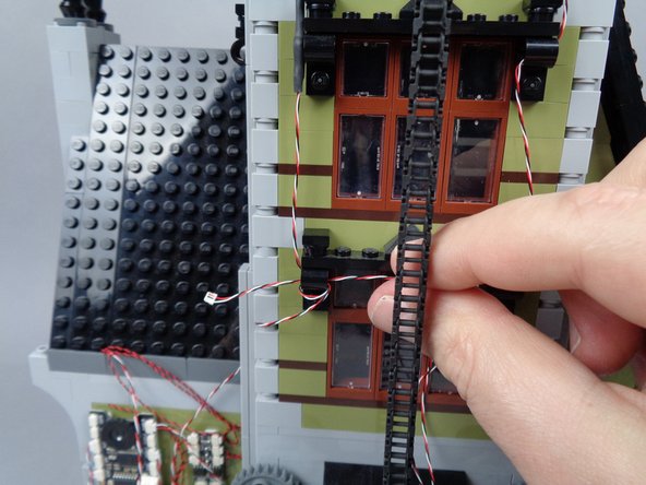 Make sure the wire passes behind the elevator chain, as shown by the red circle in the first photo.