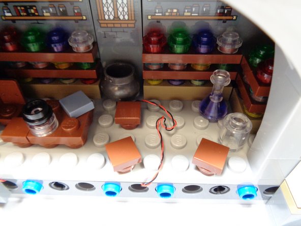 As shown in the first photo, coil up any excess wire from the cauldron light into the space that will be covered up by the table.