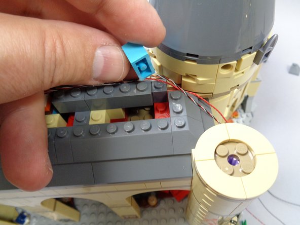 As shown in the third photo, remove the light blue 1x2 brick from beneath the right side of the exposed roof.