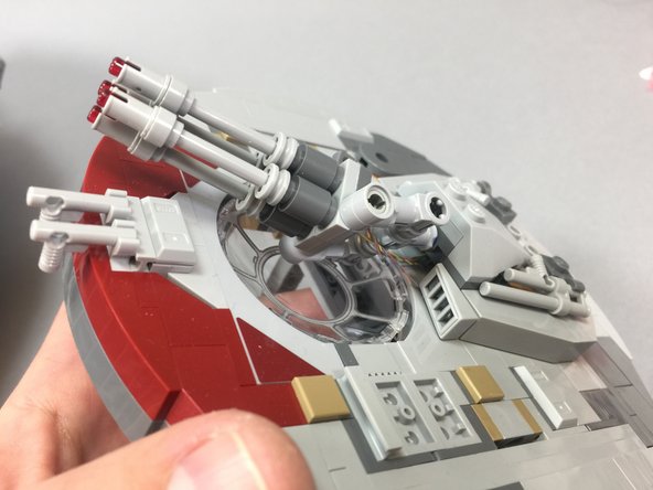 As shown by the red arrows in the first photo, pass the two pairs of LED light wires through the two OUTER Technic stud holes in the tan brick.