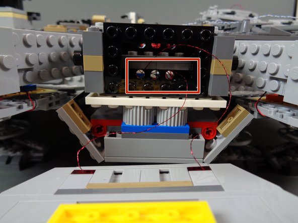 As shown by the red rectangle in the second photo, thread the wires for the two bottom lights through the Technic stud holes in the docking bay frame.