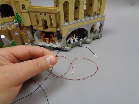 You should have two cables coming from the second section of the castle (the section you have been working on).  The first photo shows these two cables: one has black wires and the other has red and black wires.