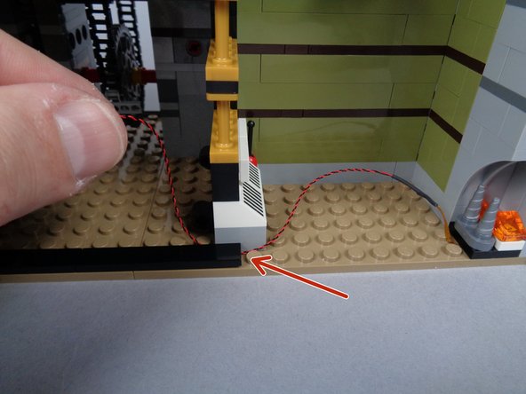 As shown in the third photo for this step, re-attach the long black tile so it holds down the fireplace light wire.