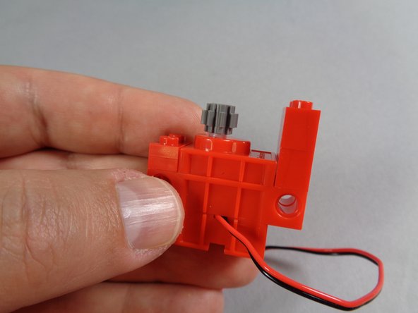 Finally, as shown in the photos for this step, attach one of the dark bluish gray gears on top of the white motor axle.  Press the gear all the way down so it covers the white axle.