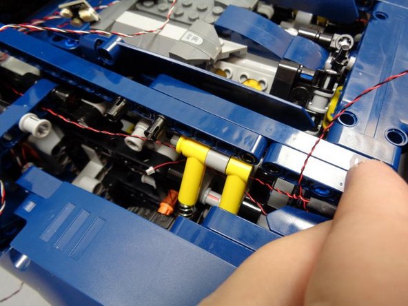 As shown in the photos for this step, route the wires for the left and right tail light LEDs behind the yellow shock absorbers like you did earlier with the turn signal wires.