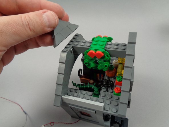As shown in the photos for this step, remove the front and back roof slope sections above the cross-beam (the part with the wreaths), then remove the two cross-beam sections as well.