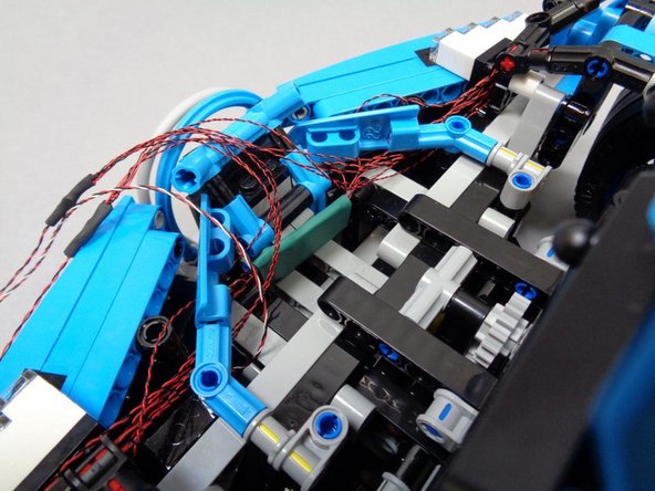 The circuit board with the green covering should sit in the center of the area behind the front grille, as shown in the photos.