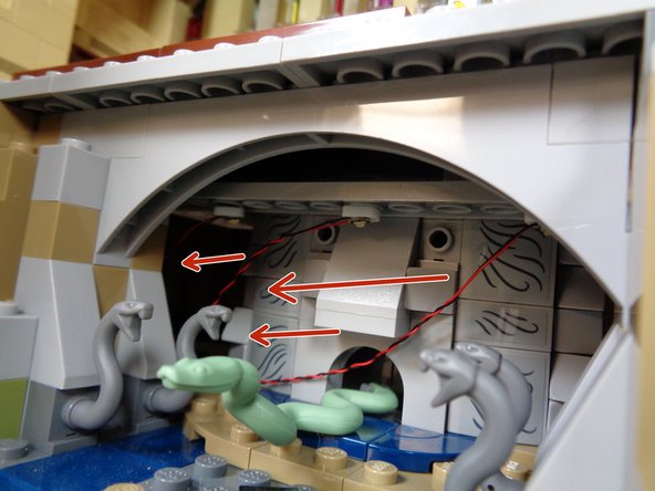 As shown by the red arrows in the first photo, feed the wires for the three lights in the Chamber of Secrets into the opening at the left.