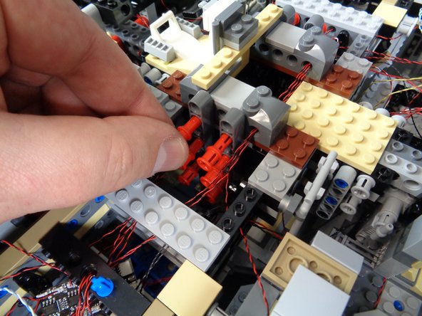 Carefully re-attach the lower mount to the main frame of the Falcon as shown in the first photo. Carefully re-insert each of the 12 red Technic pins to hold the lower mount firmly in place.