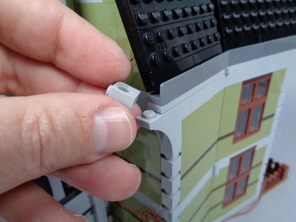 As shown in the photos for this step, run the 3-wire cable up to the roof of the mansion and use the 1x1 Technic brick to hold it in place.