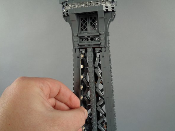 As shown in the photos for this step, next you will attach the top section (the 20-LED strip section) of light strip #2 to the inside of the tower frame.