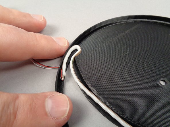 As shown by the orange arrow in the second photo for this step, begin by inserting the LED strip into the bottom of the frame with the wire passing through the notch at the bottom edge.